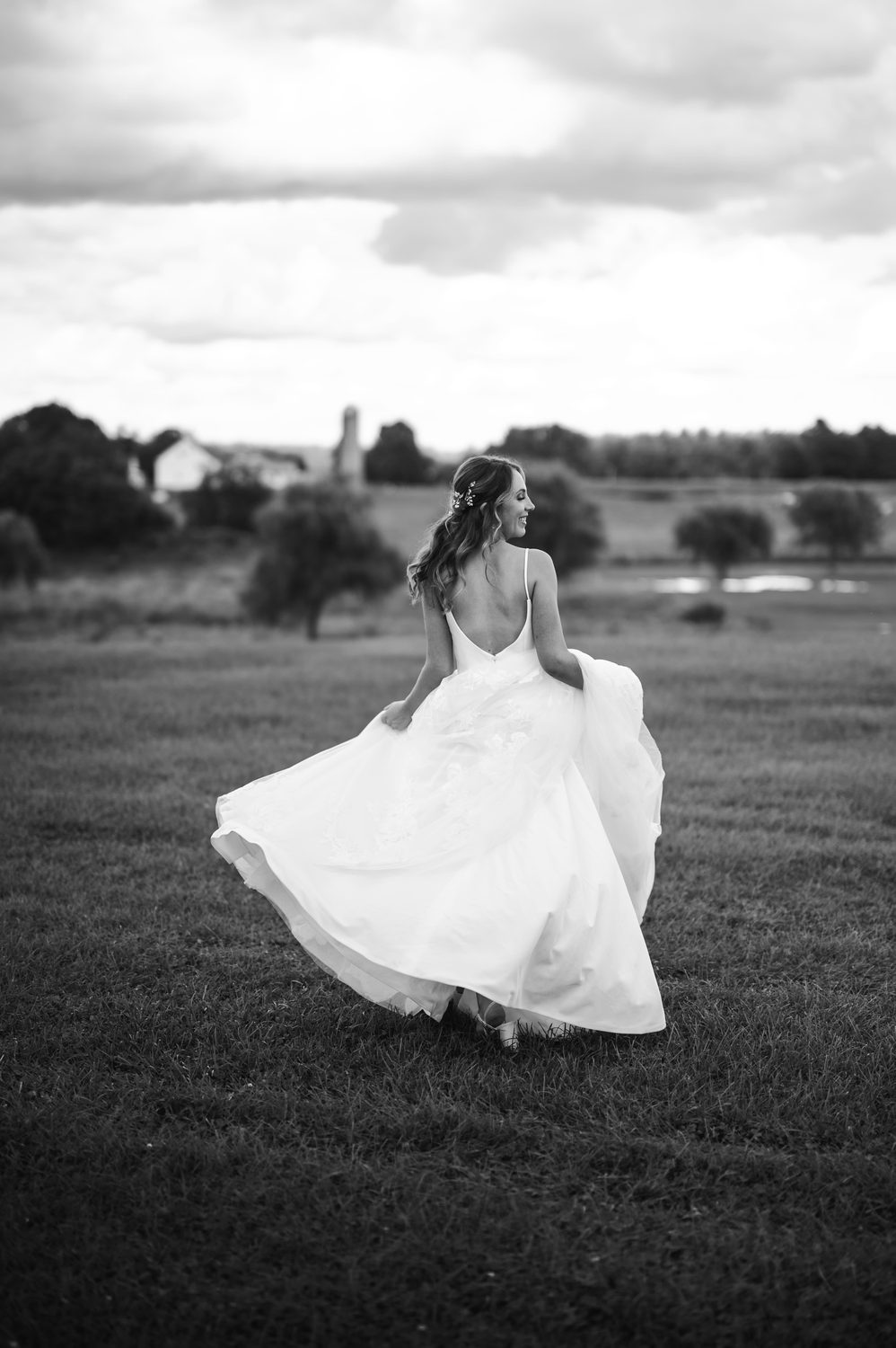 Bride twirling her gown in a New England farm field, black and white