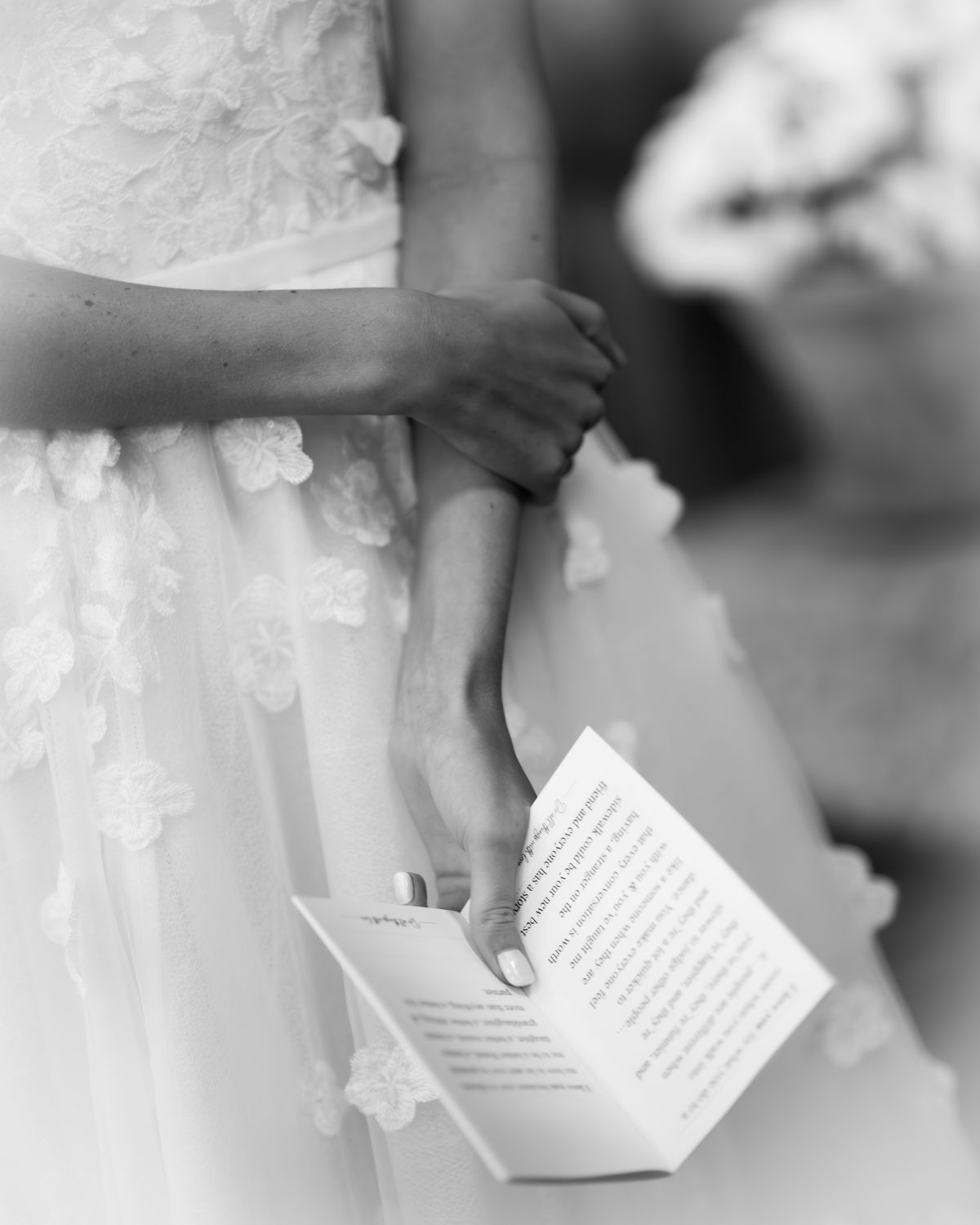 Close up of the bride holding her vows, hands clasped, black and white